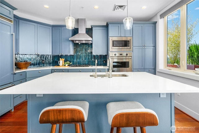 6801 Greenwood Ave N Unit 403, Seattle, WA 98103 - kitchen with wall chimney exhaust hood, appliances with stainless steel finishes, backsplash, light countertops, and recessed lighting