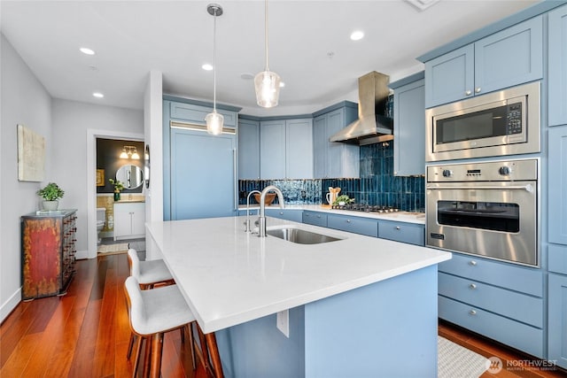 6801 Greenwood Ave N Unit 403, Seattle, WA 98103 - kitchen featuring stainless steel appliances, wall chimney exhaust hood, light countertops, dark wood-style floors, and recessed lighting