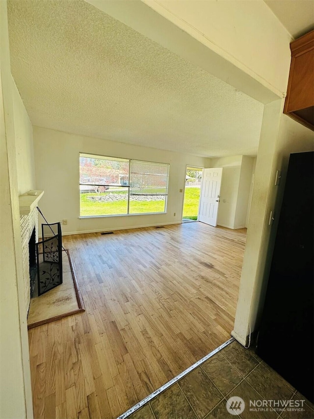 7702 202nd Pl SW, Edmonds, WA 98026 - unfurnished living room with a fireplace, a textured ceiling, and wood finished floors