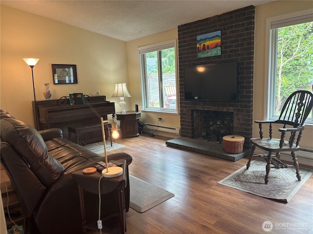 12611 50th Dr SE, Everett, WA 98208 - living area with wood finished floors, a baseboard heating unit, a textured ceiling, and a fireplace