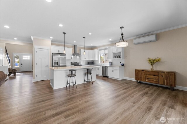 225 N Mcneely St, Buckley, WA 98321 - kitchen with wall chimney range hood, appliances with stainless steel finishes, a center island, a wall mounted air conditioner, and ornamental molding