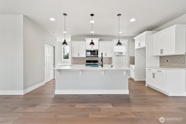 15705LOT13 SE 257th St, Covington, WA 98042 - kitchen with stainless steel microwave, stove, backsplash, light wood finished floors, and recessed lighting