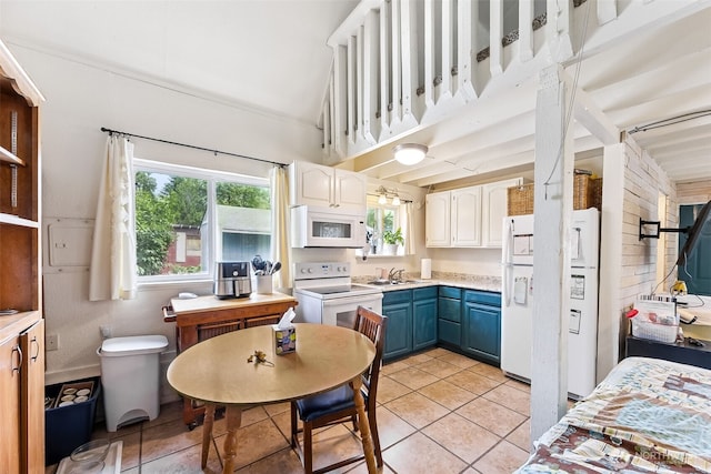 9317 214th Ave E, Bonney Lake, WA 98391 - kitchen with white appliances, blue cabinetry, light tile patterned floors, light countertops, and vaulted ceiling