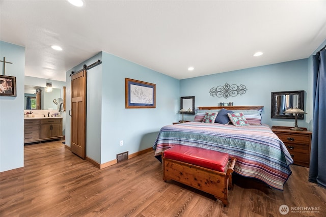 9317 214th Ave E, Bonney Lake, WA 98391 - bedroom with a barn door, wood finished floors, recessed lighting, and connected bathroom