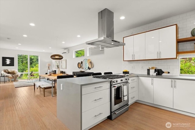 4603 S Juneau St, Seattle, WA 98118 - kitchen with island exhaust hood, stainless steel gas range oven, a peninsula, white cabinets, and open floor plan