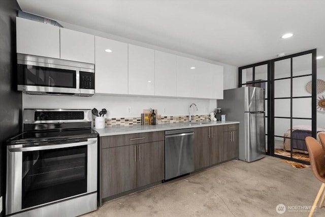 4603 S Juneau St, Seattle, WA 98118 - kitchen featuring appliances with stainless steel finishes, white cabinets, concrete flooring, light countertops, and backsplash