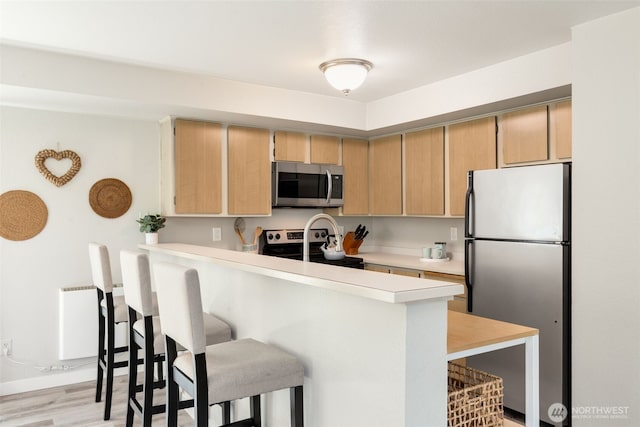 29 Etruria St Unit B505, Seattle, WA 98109 - kitchen with stainless steel appliances, a breakfast bar area, light countertops, and light brown cabinets