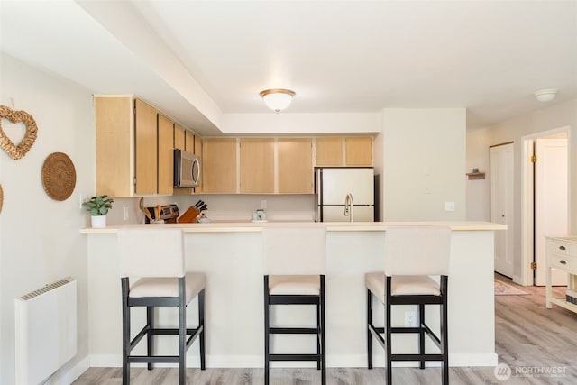 29 Etruria St Unit B505, Seattle, WA 98109 - kitchen featuring stainless steel microwave, white refrigerator, radiator, light brown cabinets, and a peninsula