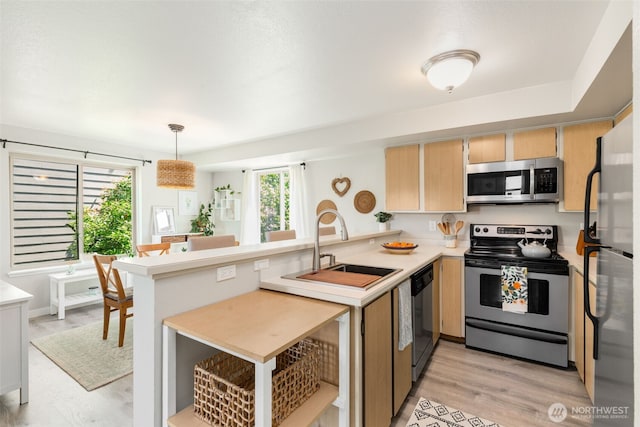 29 Etruria St Unit B505, Seattle, WA 98109 - kitchen with stainless steel appliances, a peninsula, light countertops, light brown cabinets, and hanging light fixtures