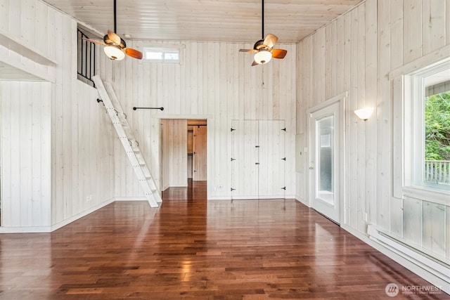 13540 E State Route 106, Belfair, WA 98528 - unfurnished living room featuring ceiling fan, a baseboard heating unit, wood finished floors, wood walls, and a towering ceiling