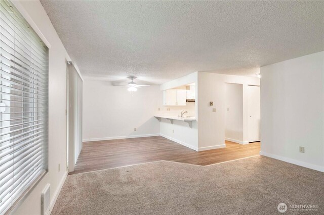 3834 D Pl SE, Auburn, WA 98002 - unfurnished living room with light carpet, a textured ceiling, a ceiling fan, and light wood-style floors