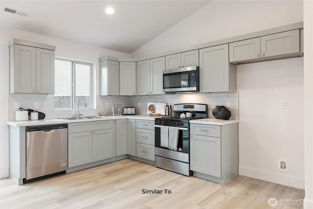 314 N Sandy Loop, Moses Lake, WA 98837 - kitchen with appliances with stainless steel finishes, gray cabinetry, vaulted ceiling, tasteful backsplash, and light wood-style floors
