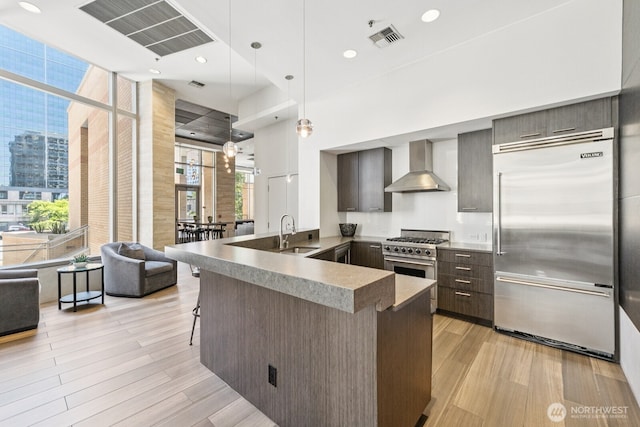 10610 NE 9th Pl Unit C4210, Bellevue, WA 98004 - kitchen featuring wall chimney range hood, premium appliances, a kitchen bar, light wood-style flooring, and recessed lighting