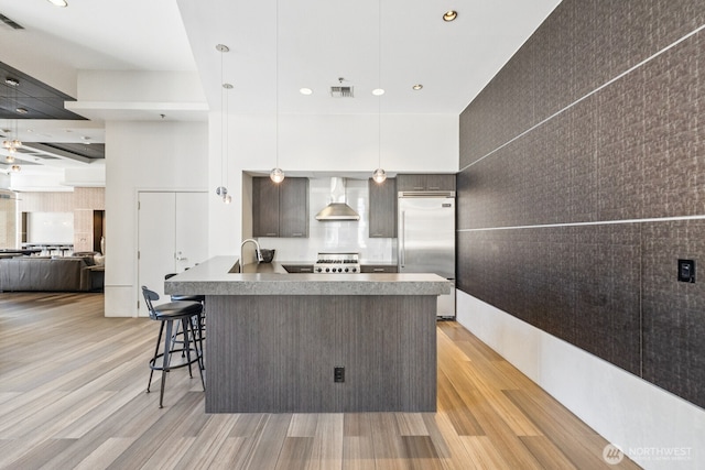 10610 NE 9th Pl Unit C4210, Bellevue, WA 98004 - kitchen featuring built in fridge, wall chimney range hood, light wood-style floors, open floor plan, and a breakfast bar area