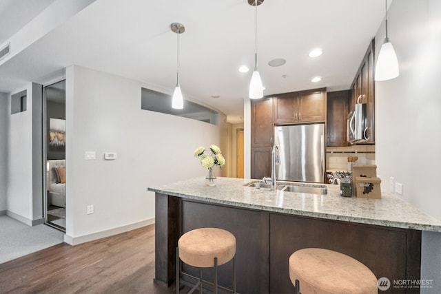 10610 NE 9th Pl Unit C4210, Bellevue, WA 98004 - kitchen featuring stainless steel appliances, a peninsula, wood finished floors, light stone counters, and hanging light fixtures