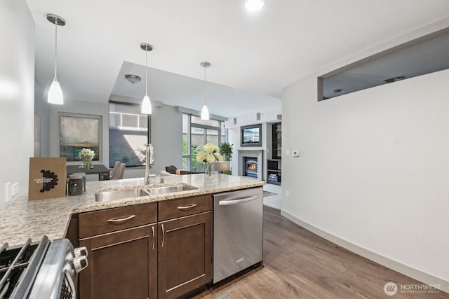 10610 NE 9th Pl Unit C4210, Bellevue, WA 98004 - kitchen featuring appliances with stainless steel finishes, dark brown cabinets, light wood-type flooring, a lit fireplace, and pendant lighting
