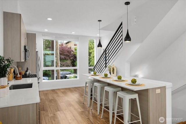 9030 18th Ave SW Unit E, Seattle, WA 98106 - kitchen featuring stainless steel microwave, modern cabinets, light countertops, a breakfast bar, and light wood finished floors