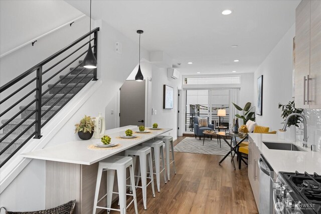 9030 18th Ave SW Unit E, Seattle, WA 98106 - kitchen with appliances with stainless steel finishes, wood finished floors, a kitchen breakfast bar, light countertops, and recessed lighting