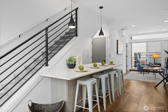 9030 18th Ave SW Unit E, Seattle, WA 98106 - kitchen featuring wood finished floors, pendant lighting, recessed lighting, a breakfast bar area, and a wall mounted AC