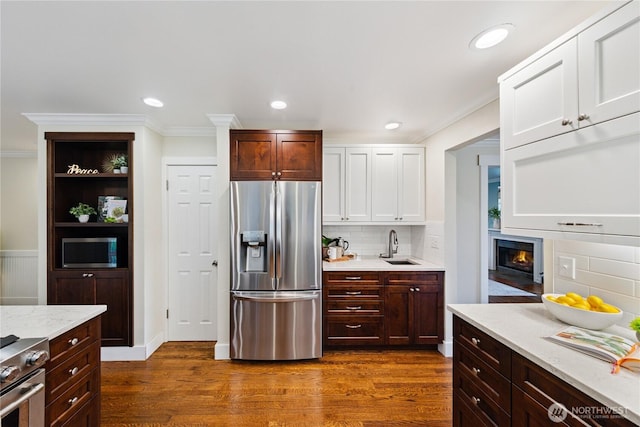 2515 16th St, Anacortes, WA 98221 - kitchen with appliances with stainless steel finishes, crown molding, white cabinetry, dark wood finished floors, and tasteful backsplash