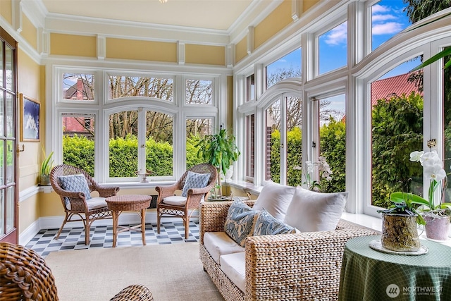 sunroom with tile patterned floors, crown molding, french doors, and a high ceiling