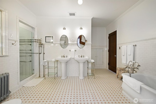 bathroom featuring ornamental molding, a bath, radiator, tile walls, and a shower stall
