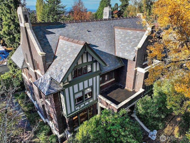 back of property featuring a chimney and a high end roof