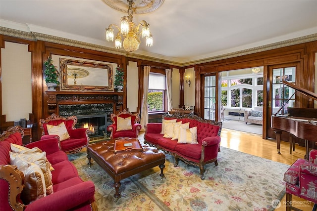 living room featuring ornamental molding, a high end fireplace, a chandelier, and wood finished floors
