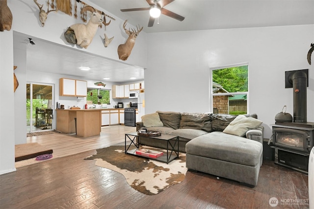 6258 Bellwood Dr, Maple Falls, WA 98266 - living area featuring a wood stove, ceiling fan, plenty of natural light, light wood-type flooring, and a towering ceiling