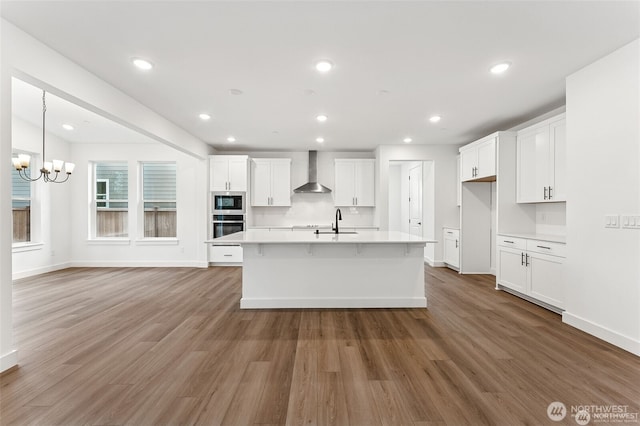 13937 181st St E Unit 8, Puyallup, WA 98374 - kitchen featuring wall chimney exhaust hood, appliances with stainless steel finishes, wood finished floors, white cabinetry, and light countertops