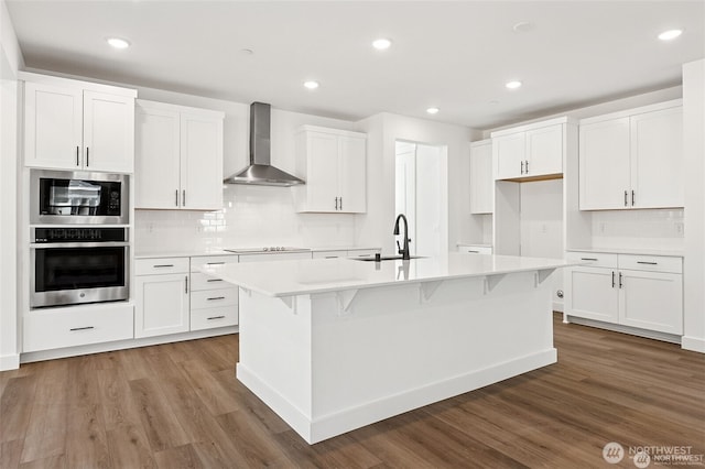 13937 181st St E Unit 8, Puyallup, WA 98374 - kitchen featuring appliances with stainless steel finishes, wall chimney exhaust hood, wood finished floors, white cabinets, and recessed lighting