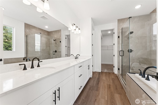 13937 181st St E Unit 8, Puyallup, WA 98374 - bathroom featuring double vanity, a shower stall, a walk in closet, wood finished floors, and recessed lighting