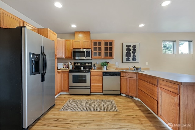 9323 4th Ave W, Everett, WA 98204 - kitchen with appliances with stainless steel finishes, a peninsula, light wood-style floors, glass insert cabinets, and light countertops