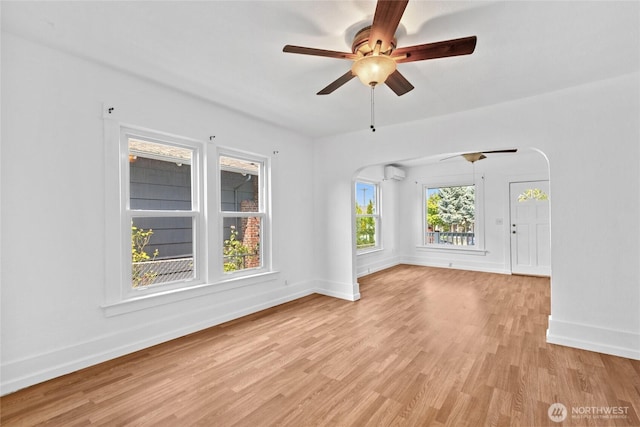 3510 S K St, Tacoma, WA 98418 - empty room featuring ceiling fan, an AC wall unit, light wood-style floors, and arched walkways