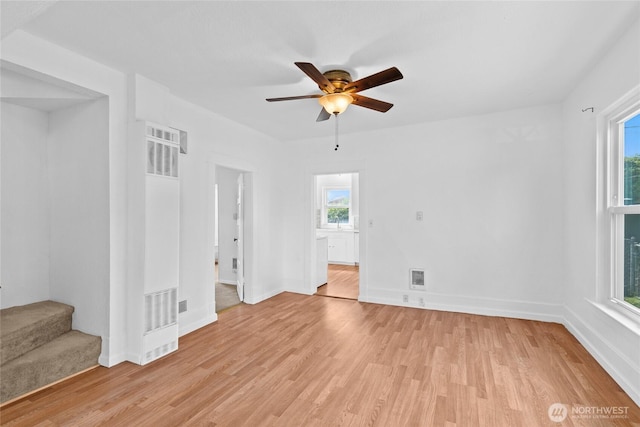 3510 S K St, Tacoma, WA 98418 - empty room featuring a heating unit, light wood-style flooring, a ceiling fan, and stairs