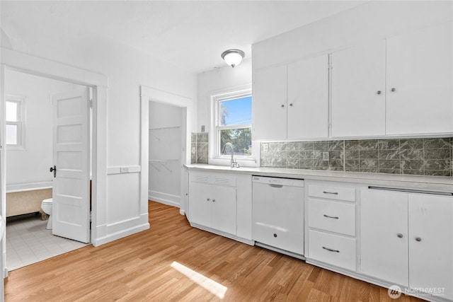 3510 S K St, Tacoma, WA 98418 - kitchen with white dishwasher, light countertops, light wood-style flooring, backsplash, and white cabinets