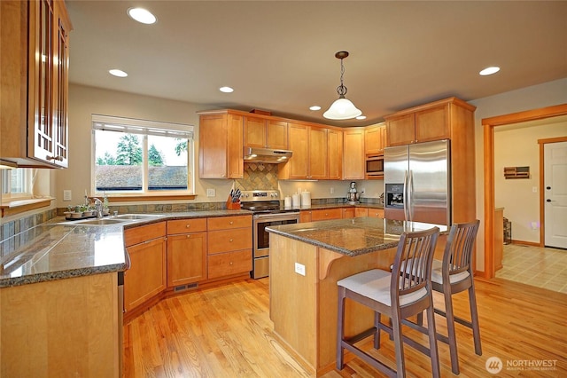 2102 256th St NW, Stanwood, WA 98292 - kitchen with appliances with stainless steel finishes, under cabinet range hood, light wood-type flooring, recessed lighting, and a kitchen bar