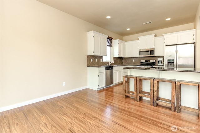 1605 Riddell Ave NE, Orting, WA 98360 - kitchen with stainless steel appliances, dark countertops, light wood-type flooring, tasteful backsplash, and recessed lighting