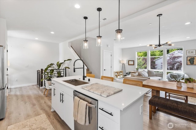 21511 50th Ave W Unit E, Mountlake Terrace, WA 98043 - kitchen with appliances with stainless steel finishes, an island with sink, white cabinets, light wood finished floors, and decorative light fixtures