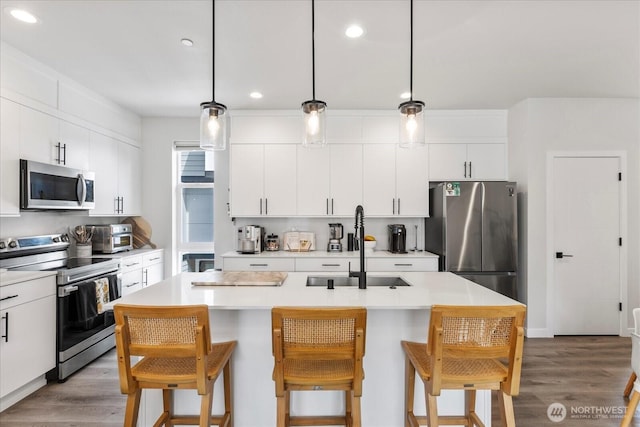 21511 50th Ave W Unit E, Mountlake Terrace, WA 98043 - kitchen featuring appliances with stainless steel finishes, recessed lighting, a breakfast bar area, light wood finished floors, and light countertops
