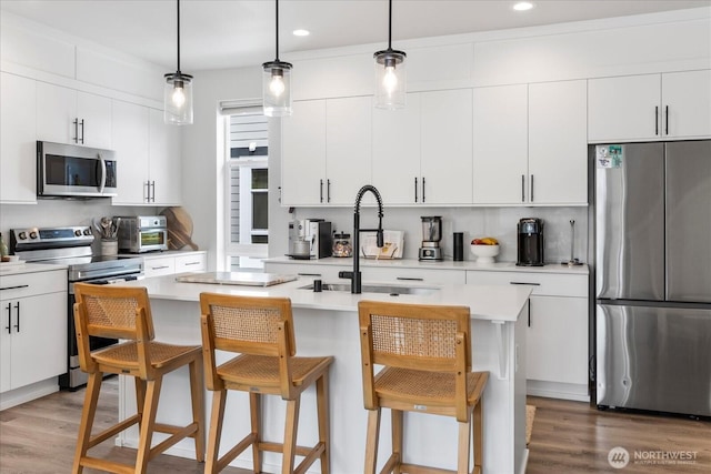 21511 50th Ave W Unit E, Mountlake Terrace, WA 98043 - kitchen featuring appliances with stainless steel finishes, light wood finished floors, a breakfast bar area, a center island with sink, and recessed lighting