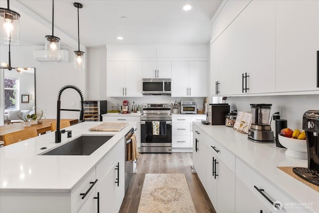 21511 50th Ave W Unit E, Mountlake Terrace, WA 98043 - kitchen featuring appliances with stainless steel finishes, wood finished floors, light countertops, recessed lighting, and a kitchen island with sink