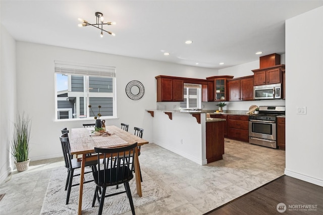4246 Stonecrest Ct, Bellingham, WA 98226 - kitchen with appliances with stainless steel finishes, a peninsula, a kitchen breakfast bar, a chandelier, and glass insert cabinets