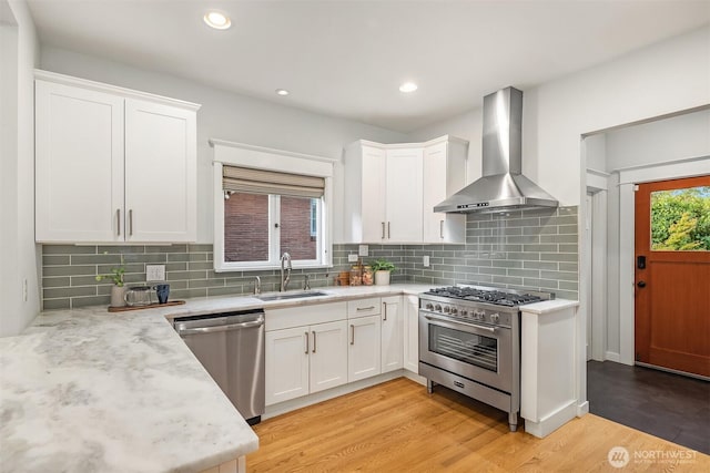 2836 32nd Ave S, Seattle, WA 98144 - kitchen with stainless steel appliances, wall chimney range hood, light wood-type flooring, white cabinetry, and recessed lighting