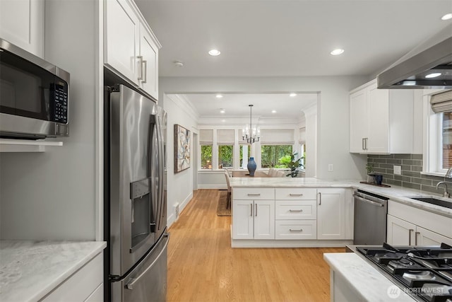 2836 32nd Ave S, Seattle, WA 98144 - kitchen featuring appliances with stainless steel finishes, light wood finished floors, white cabinetry, a peninsula, and a chandelier