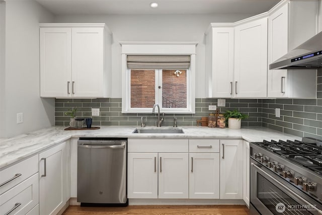 2836 32nd Ave S, Seattle, WA 98144 - kitchen featuring appliances with stainless steel finishes, wall chimney range hood, white cabinets, backsplash, and light stone counters