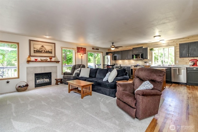15205 197th St E, Orting, WA 98360 - living room with a tile fireplace, a ceiling fan, and light wood-type flooring