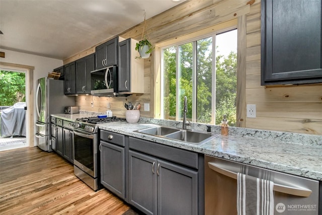 15205 197th St E, Orting, WA 98360 - kitchen with appliances with stainless steel finishes, light wood-type flooring, plenty of natural light, wood walls, and light stone counters