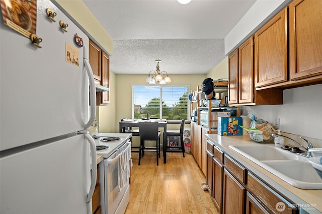 3590 Narrows View Ln NE Unit 203, Bremerton, WA 98310 - kitchen featuring white appliances, light countertops, brown cabinets, a chandelier, and light wood finished floors