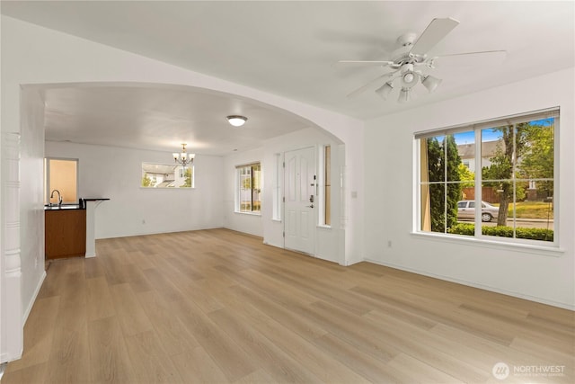331 Index Ave SE, Renton, WA 98056 - unfurnished living room with light wood-type flooring, a ceiling fan, a chandelier, and arched walkways